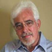 Elderly man with glasses and white hair.