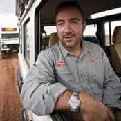 Man in vehicle on dirt road.