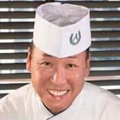 Smiling chef in white uniform and hat.
