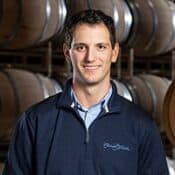 Man standing in front of wine barrels.