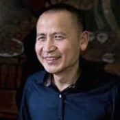 Smiling man in a dark shirt.