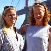 Two women smiling by Golden Gate Bridge.