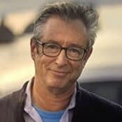 Man wearing glasses, smiling outdoors.