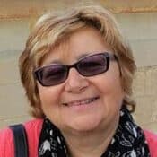 Smiling person wearing sunglasses and scarf.
