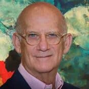 Man with glasses in front of colorful background.