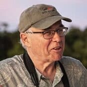 Man wearing cap and glasses outdoors.