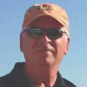 Man wearing cap and sunglasses outdoors.
