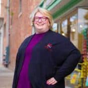 Person smiling in front of a store.
