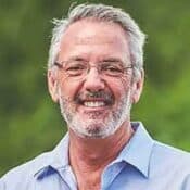 Smiling man with glasses and gray hair.
