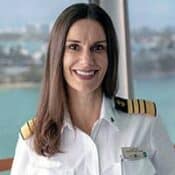 Smiling woman in captain's uniform indoors.