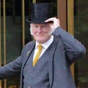 Man in suit and top hat smiling.