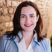 Woman smiling against a brick wall background.
