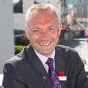 Smiling man in a suit outdoors.