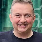 Smiling man in front of green background.
