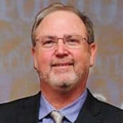 Man in suit with glasses and beard.
