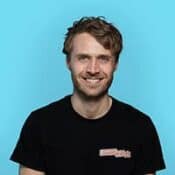 Man smiling against a blue background.
