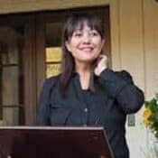 Woman smiling outdoors near a podium.