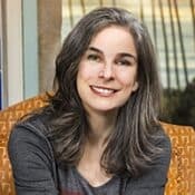 Smiling person sitting on an orange chair.