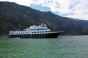 Luxury yacht cruising by mountainous landscape.