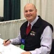 Man sitting at a conference table smiling.