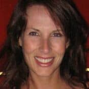 Smiling woman with dark hair against red background.