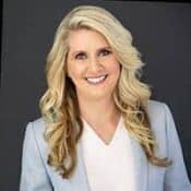 Blonde woman smiling in professional attire.