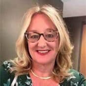Smiling woman with glasses and blonde hair.