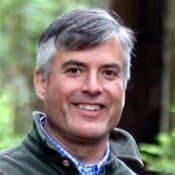 Smiling man outdoors with gray hair.