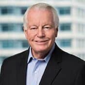 Elderly man smiling in suit and shirt.