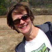 Smiling person outdoors wearing sunglasses and jacket.