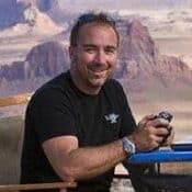 Man smiling with mountains in background.