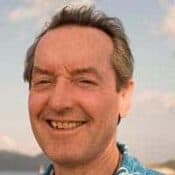Smiling man outdoors with blurred background.